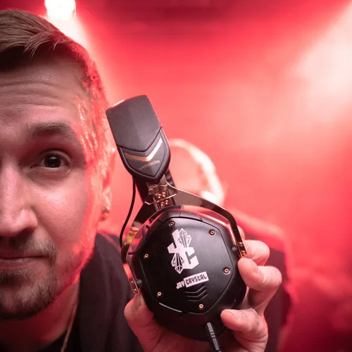 Jay Crystal holding his headphones in red club lights